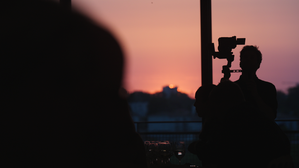 A camera operator filming at sunset