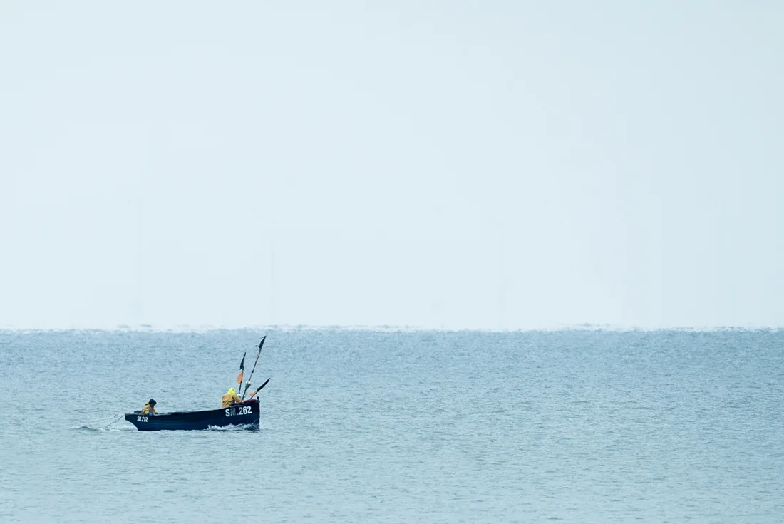 A fishing boat on a pale blue sea