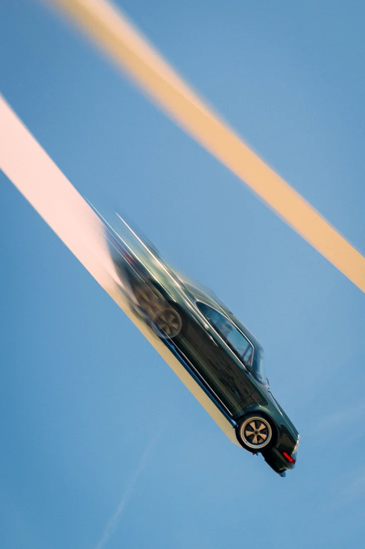 A blurred car against blue and diagonal bands of colour