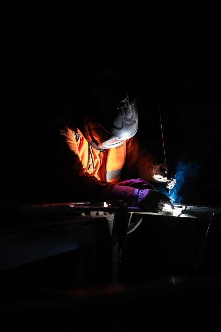 A welder illuminated by the light of their work