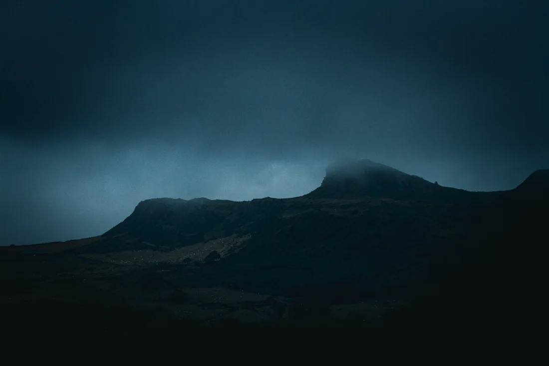Low cloud drifting over a dark mountain ridge