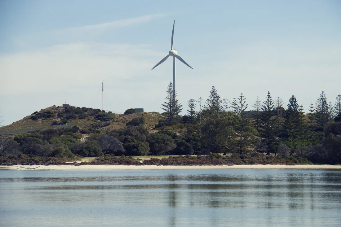 A wind turbine above a quiet shoreline