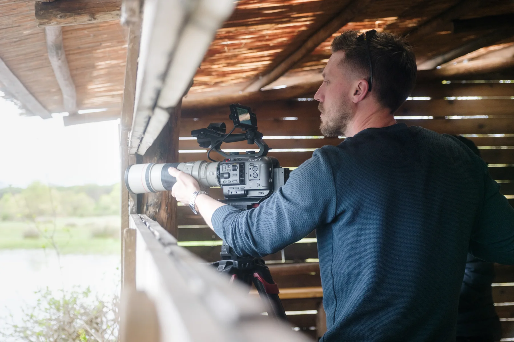 Lewis filming wildlife from a wooden hide